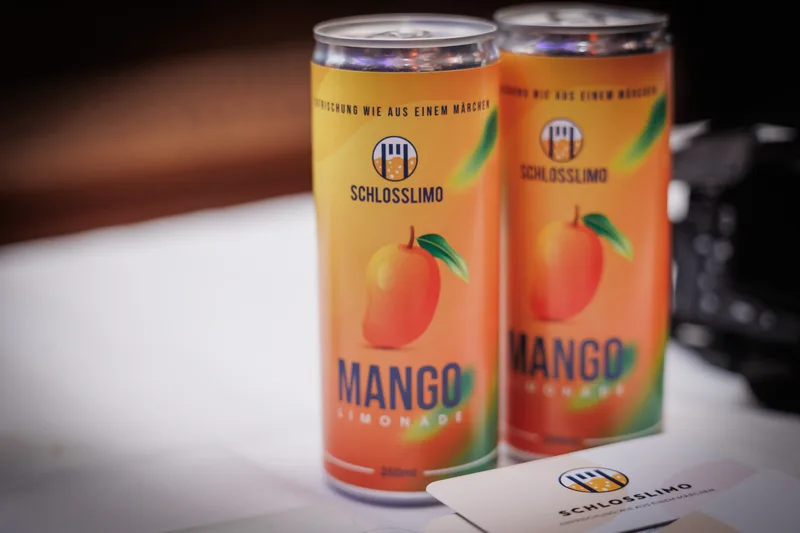 Zwei Dosen Schlosslimo Mango auf einem Tisch bei einer Veranstaltung.