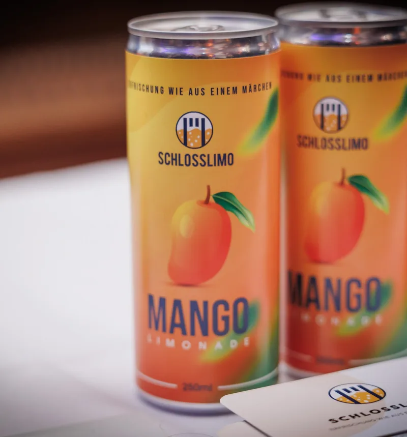 Zwei Dosen Schlosslimo Mango vor hellem Hintergrund.